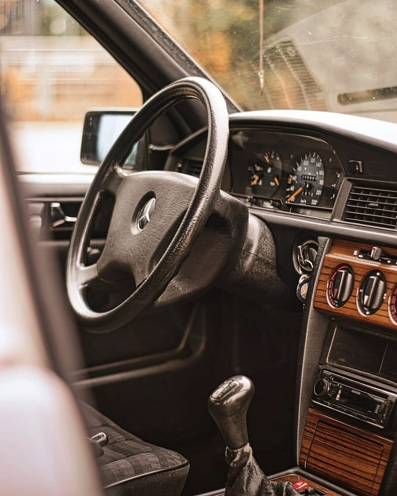 Mercedes-Benz 190E W201 Klassiker in warmer Lichtstimmung fotografiert auf urbanem Gelände – Automotive Fotografie Detailaufnahme Front und Seitenansicht