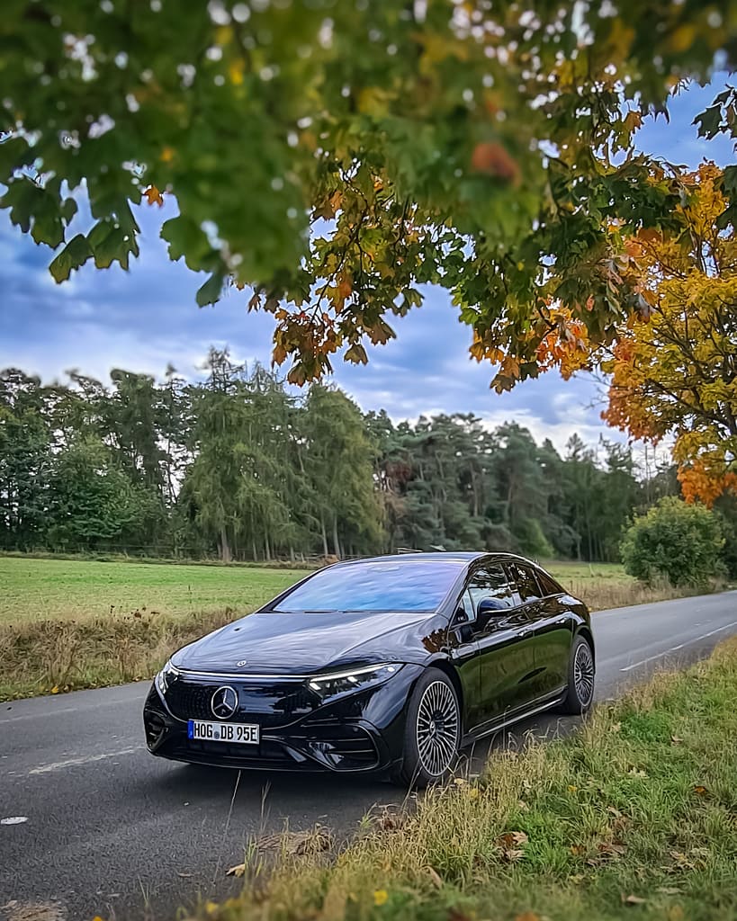 Mercedes-Benz EQS 450+ Frontansicht auf Landstraße unter Herbstbaum