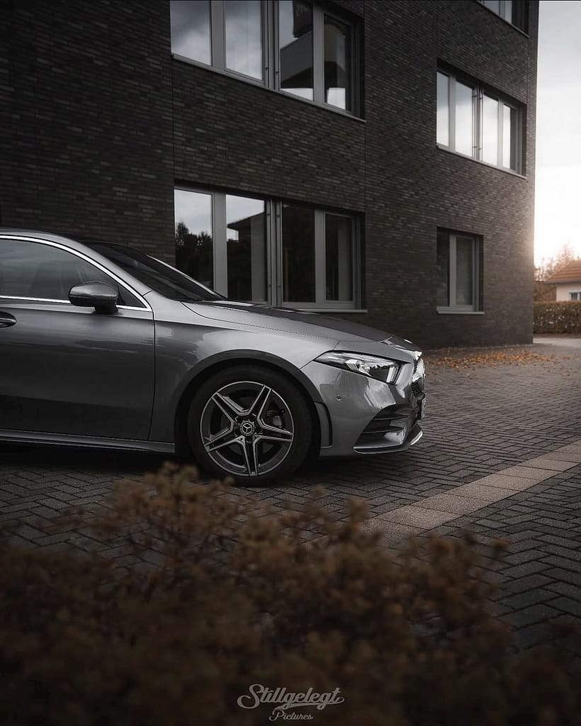 Mercedes-Benz A-Klasse W177 in grauer Lackierung in Seitenansicht vor moderner Architektur bei Sonnenuntergang